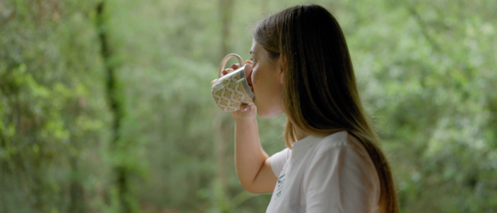 Noia en prenent cafè en un bosc